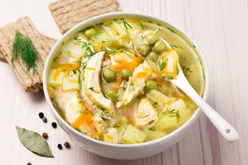 Chicken vegetable soup with ingredients in a white bowl.