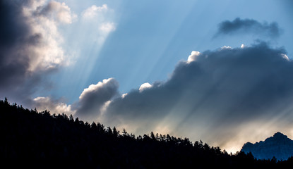 Sonne, Wolken und blauer Himmel sind über dem Wald nach Sonnenaufgang zu sehen