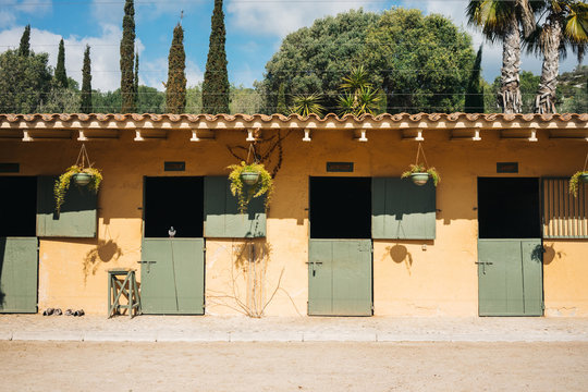 Empty stables for horses with yellow wall and green doors on ranch