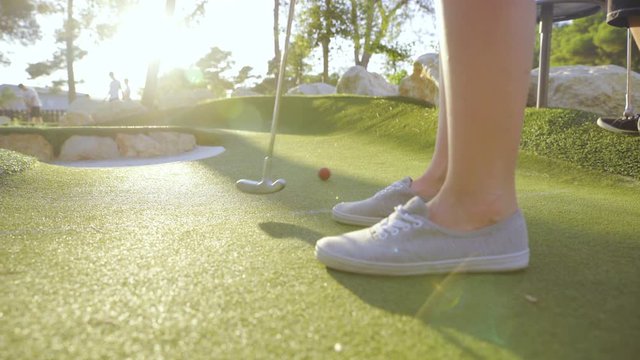 Moving camera around person hitting golf ball towards sunset 4K