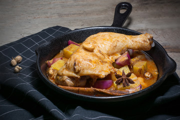 Low key of image of Chicken thighs in a cast iron skillet and sweet potato on wooden background