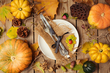 Autumn background with plate, fall leaves and pumpkin over wooden table. View from above