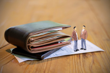 Soft tone of figure of businessman with  Money and credit card in a leather wallet on wooden table and bill slip background.