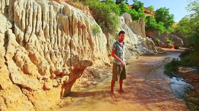 Closeup tall young man makes selfie in large yellow rock background on Fairy Stream in Vietnam