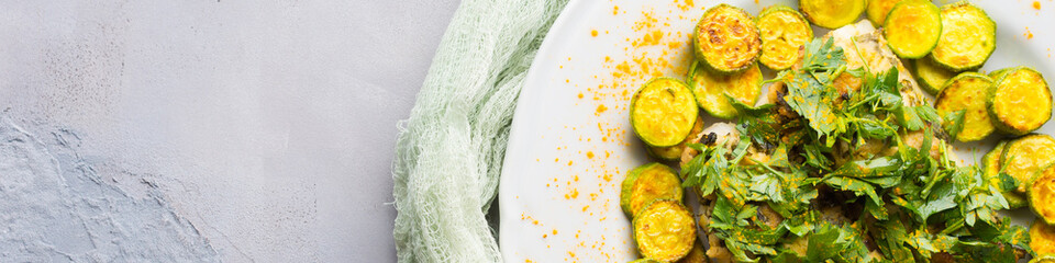 Baked Stock fish fillet with almond parsley topping and turmeric courgettes on white plate. Healthy diet dish