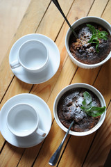 Healthy breakfast of oat pudding in white keraimic mold. Decorated with sprig of mint and powdered sugar. Two empty cups