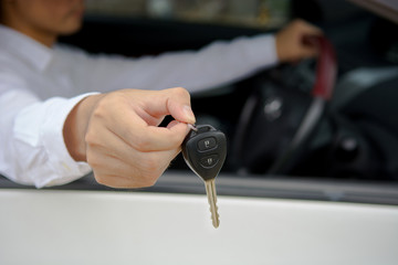 Man handing car key while sitting in the car, car for sale or for rent concept.