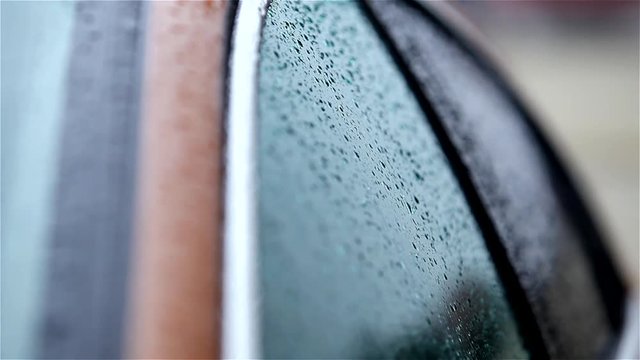 Raindrops flow down the car glass