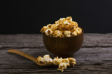 Caramel popcorn in the bowl wooden background.