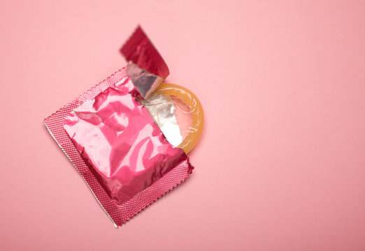 pink condom isolated on pink background photo, hiv prevention concept