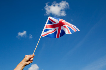 British flag in hand against blue sky.