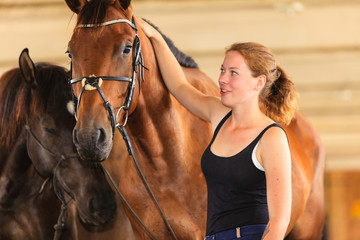 Obraz premium Jockey young girl petting and hugging brown horse