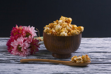 Caramel popcorn in the bowl wooden background.
