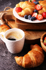 Delicious breakfast with fresh croissants and ripe berries on old marble background