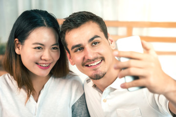 Fototapeta premium Handsome Man and His Wife are Making Selfie in Bedroom - Warm Family Concept