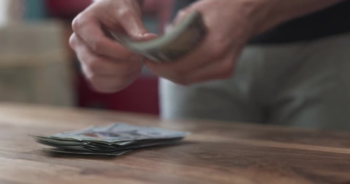 front shot of man counting dollars on wood table fast video