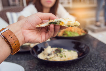 Close-up of hand holding pizza. spinach and cheese italian pizza with blur of Italian food background.(vintage tone)