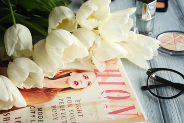 Beautiful composition of cosmetics and magazine with tulips on table