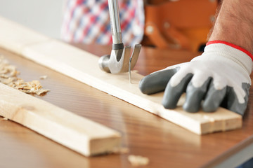Carpenter pulling out nail from wooden plank, closeup