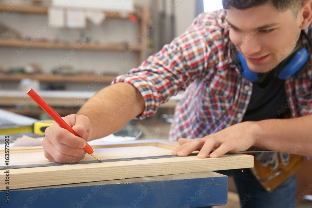 Canvas Prints carpenter applying marking onto wooden board in workshop