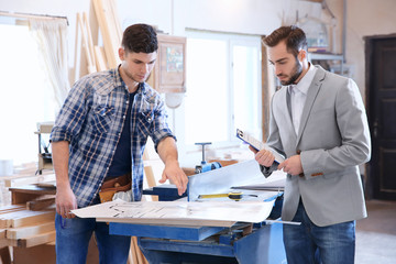 Young carpenter and customer in workshop