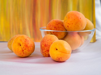 Bright yellow and orange auricos on a white tablecloth in a glass vase