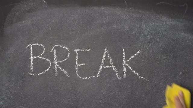 Woman's hand writing "BREAK" with white chalk on blackboard - Powered by Adobe