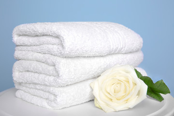 Fototapeta na wymiar Stack of clean white towels and beautiful rose on table