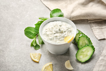 Obraz na płótnie Canvas Delicious yogurt sauce in bowl with ingredients on kitchen table