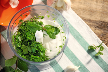 Ingredients for preparing yogurt sauce in blender bowl on kitchen table