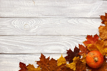 Autumn leaves and pumpkins over old wooden background