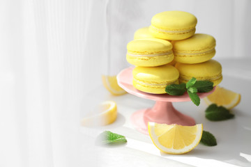 Stand with tasty lemon macarons on table