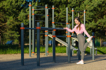 Fototapeta premium Young woman in earphones doing stretching exercises outdoor