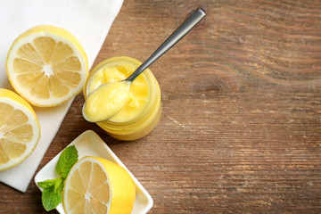 Composition with yummy lemon curd in glass jar on wooden table