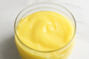 Glass jar with yummy lemon curd on light background
