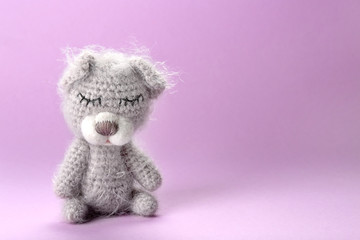 Adorable knitted baby bear toy on color background, closeup