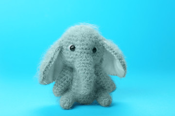 Adorable knitted baby elephant toy on color background, closeup