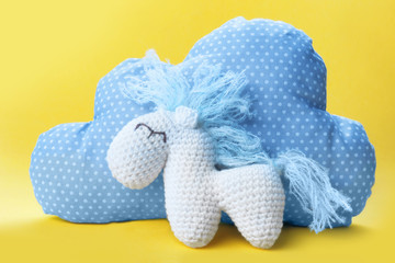 Cute handmade horse toy with pillow in shape of cloud on color background, closeup