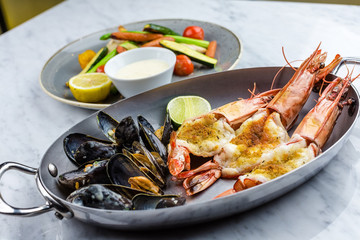 Grilled fish and vegetables with sauce with royal prowns and mussle