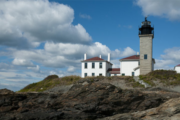 Fototapeta na wymiar Beavertail Lighthouse on top of rocky shore. It is the third oldest beacon in America.
