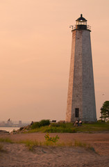 Relaxing at dusk as sun sets by File Mile Point Lighthouse near New Haven in Connecticut. - obrazy, fototapety, plakaty