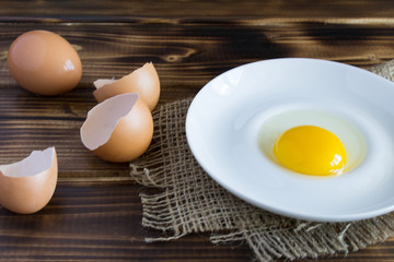 Egg yolk and egg shell on the brown wooden background