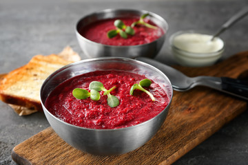 Delicious beet soup with sunflower sprouts in bowl on kitchen table