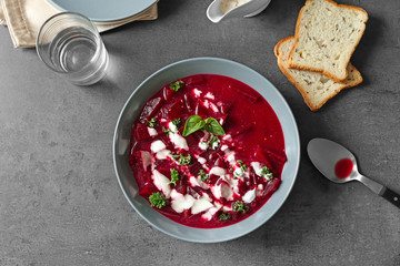 Delicious beet soup with sour cream and herbs on kitchen table