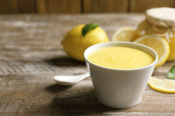 Bowl with delicious lemon curd on wooden table