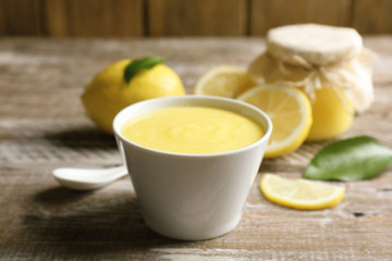 Bowl with delicious lemon curd on wooden table