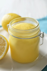 Glass jar with delicious lemon curd on table