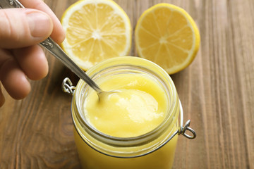Woman taking lemon curd from glass jar, closeup