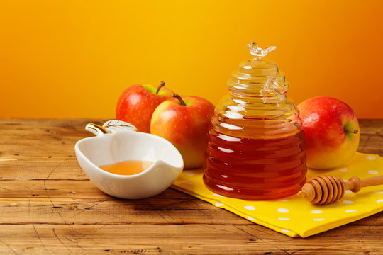 Rosh hashanah jewish new year holiday celebration concept. Honey and apples over yellow background