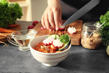 Delicious carrot salad in bowl and woman on background